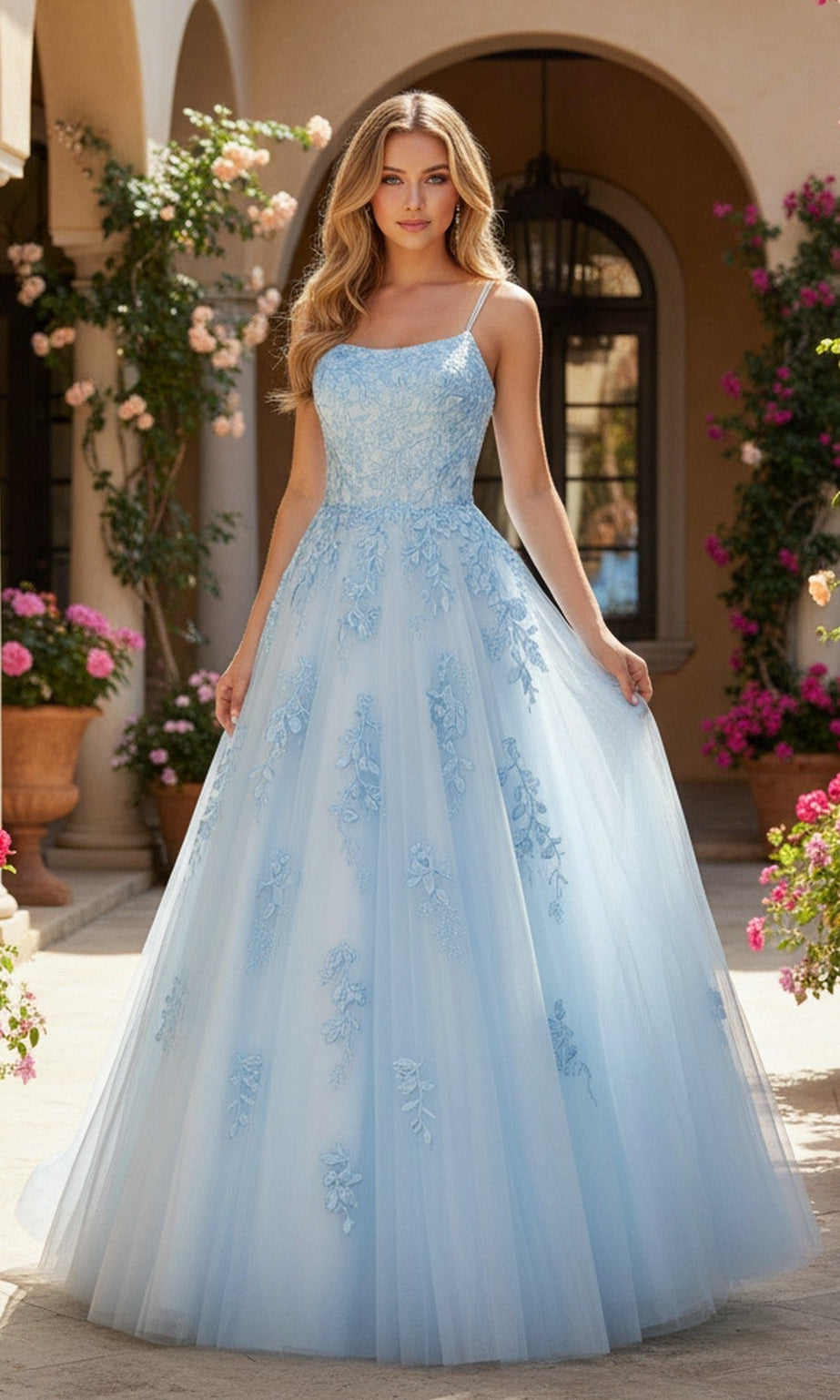 A woman stands outdoors in front of a building wearing the PromGirl Exclusive 250228 light blue long prom dress, featuring floral embroidery, a tulle overlay, and an adjustable lace-up back.